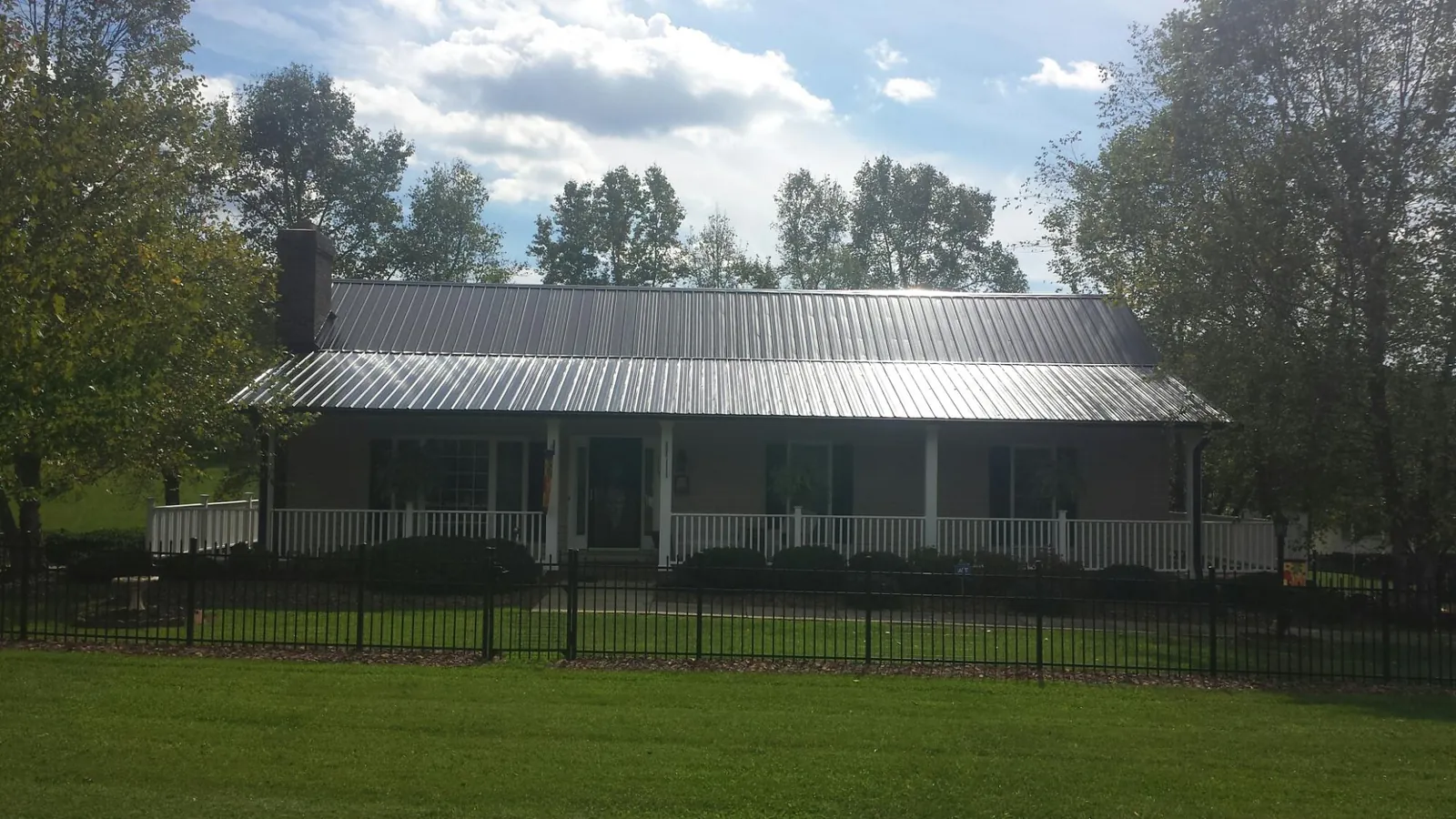 Gray metal roof on a brick ranch with a full width front porch — Gutter Guard Installation work by our crew in Dexter
